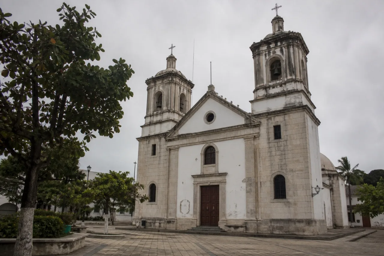Templo de dos torres y plaza empedrada en el centro de un puerto del Golfo.