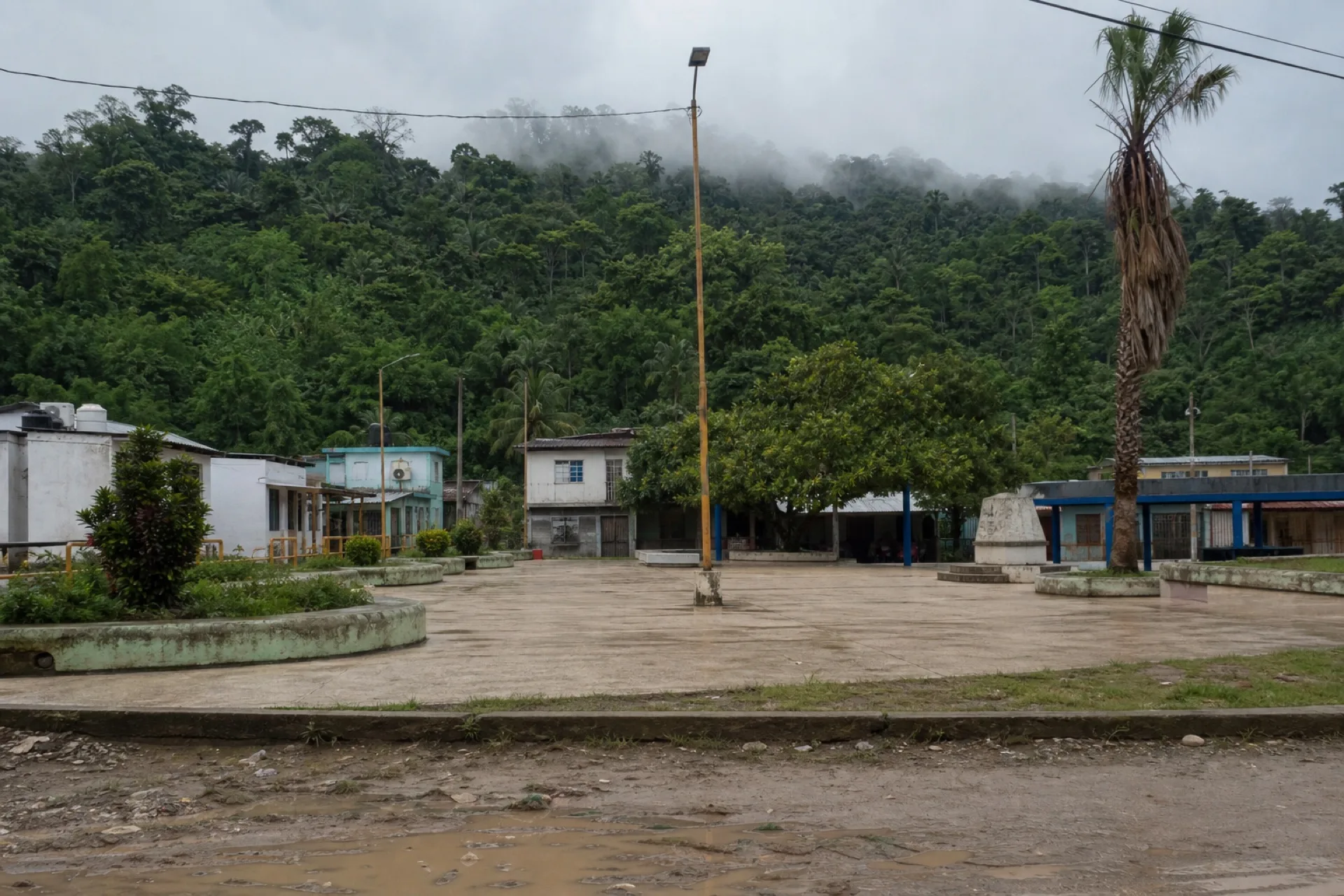 Centro de La Chinantla / Poblado 10: plaza de concreto y selva al fondo.