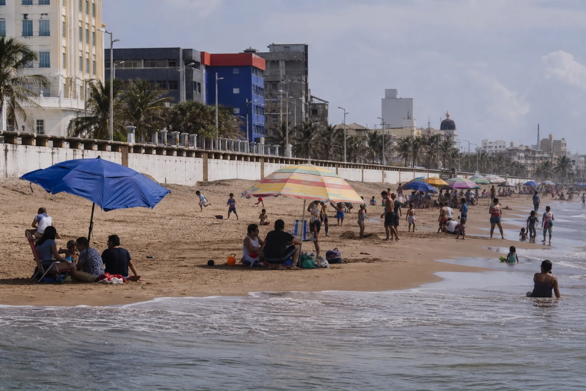 Día de playa urbana en Coatzacoalcos, sombrillas y oleaje suave.