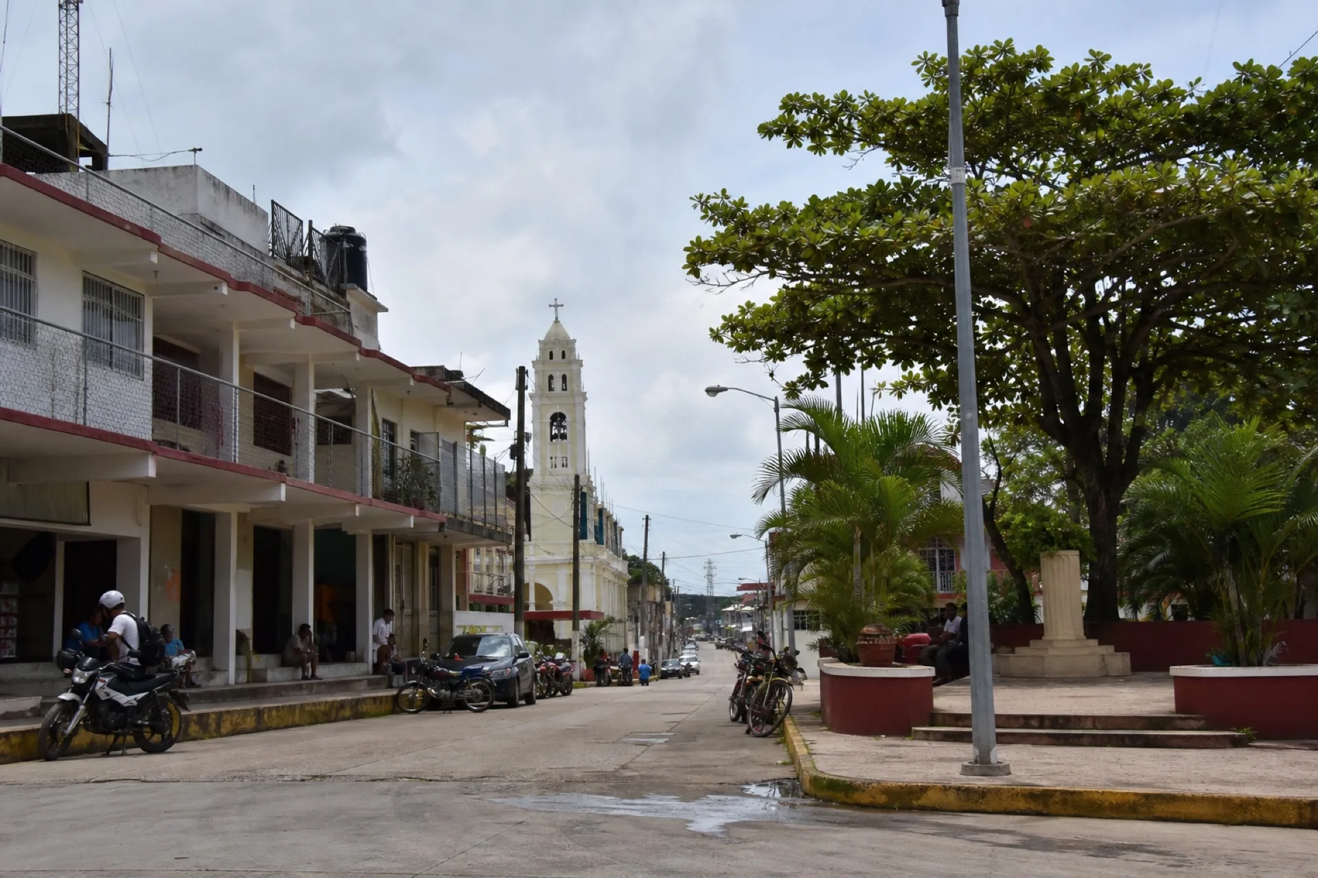 Centro de Las Choapas: calle de pueblo tropical con torre de iglesia lejana.