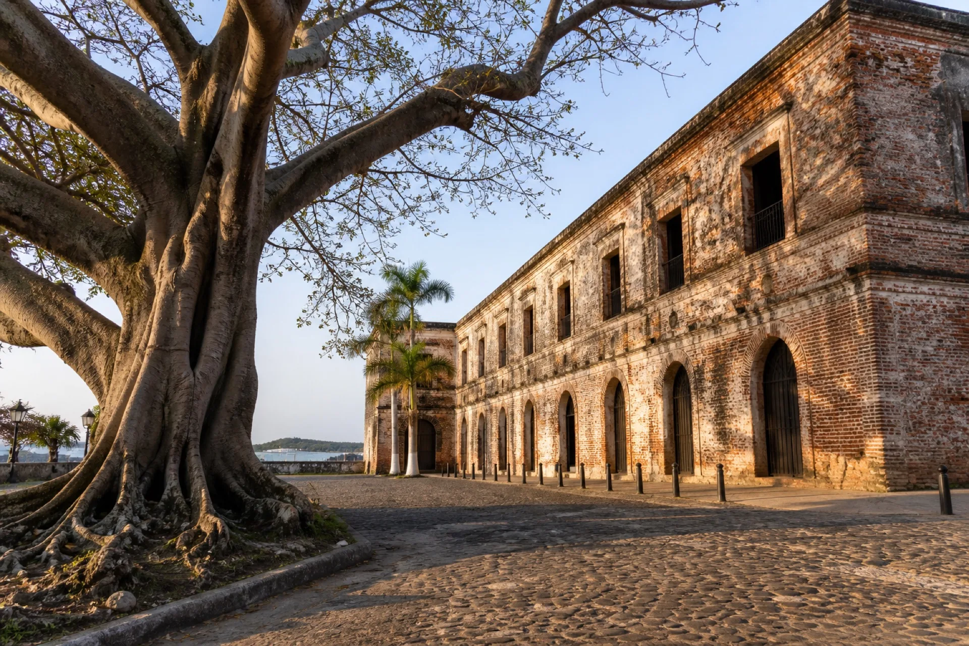 Antigua Real Aduana de ladrillo junto a una ceiba y calle empedrada en La Antigua.